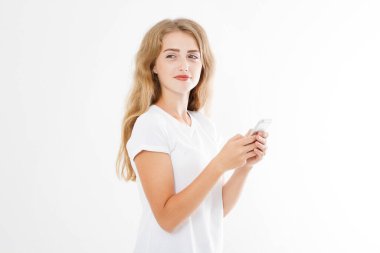 Beyaz arka planda izole edilmiş akıllı telefonunu kullanan tişörtlü güzel bir kadın. Seksi sarışın kız arkadaşıyla sohbet ediyor ya da internetten alışveriş yapıyor. Boşluğu kopyala