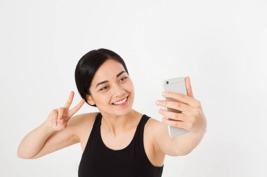 Seksi, güzel Asyalı, Koreli bir kadın selfie çekiyor ve beyaz arka planda izole edilmiş barış ya da viktory görüntüsü sergiliyor.
