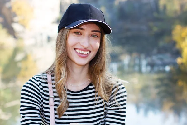 Beautiful young active woman on a background of a beautiful view of the forest and rocks. Girl wearing a cap and casual clothes - active life concept