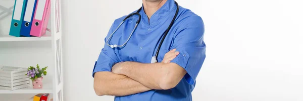 Portrait of cheerful happy male doctor in hospital with crossed hands. Surgeon with stethoscope on white background. Medical insurance.