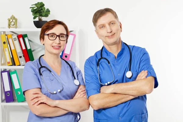 Male doctor with crossed arms and female doctor in medical office, medical insurance, copy space, selective focus.