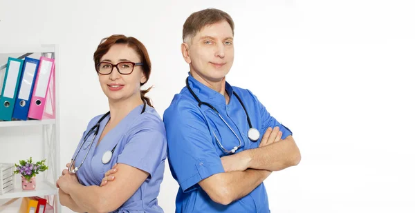 Male doctor with crossed arms and female doctor with folder in medical office, medical insurance, copy space, selective focus.
