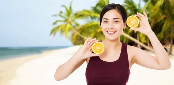 smile happy korean woman with orange slice on tropical background, summer vacation concept