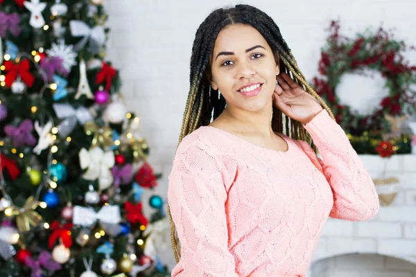 Portrait of Beautiful black Woman in Lights. Fashion and MakeUp. Christmas Santa. Elegant Lady in Red Dress over Christmas Tree Lights Background. Happy New Year.
