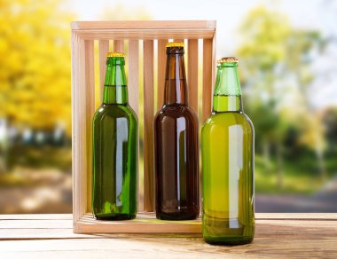 Bira şişeleri ahşap masada bulanık park arka planında