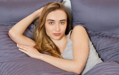 Güzel bir kadın yorganın altında yatıyordu. Başı elinde, diğeri de saçında..