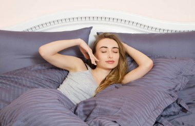 Genç ve güzel bir kadın koyu pembe odada uyanıyor.