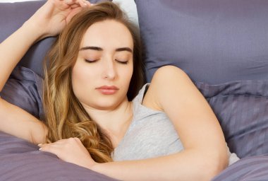 Evde yatakta uyuyan genç bir kadın portresi