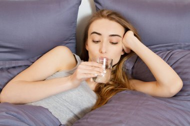 Genç bir kadın sabah bir bardak su içer, sağlıklı yaşam tarzı konsepti. Bir bardak su tutan genç güzel kız.
