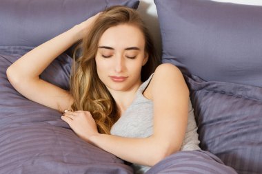 Güzel kız yatak odasında uyuyor. Yatakta uyuyan kadın, yakından çek. Genç ve güzel bir kadın uyuyor. Karanlık yatakta uyuyan güzel genç kadının portresi..