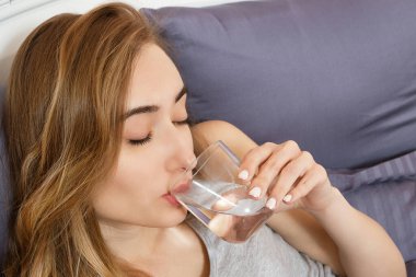 Kadın evde yatakta su içiyor, sağlık konsepti, akşamdan kalma.