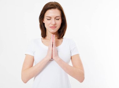 Tişörtlü esmer, beyaz arka planda gözleri kapalı dua ediyor.