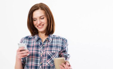 Bir fincan kahve ya da çayla gülümseyen güzel bir esmer, cep telefonundan hoş bir mesaj okuyor. Uzayı kopyala Cihazında resim izleyen kız.