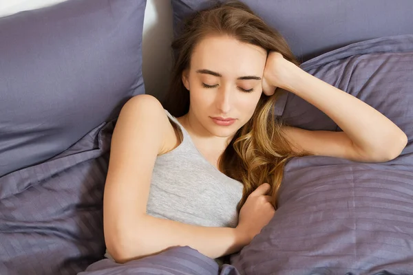 Genç ve güzel bir kadın sabahları yatakta güneşleniyor. Güzel manken yüzü kamerada seksi görünüyor, kız yatak odasında uyuyor.