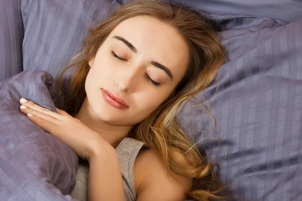 Güzel kız yatak odasında uyuyor. Yatakta uyuyan kadın, yakından çek. Genç ve güzel bir kadın uyuyor. Karanlık yatakta uyuyan güzel genç kadının portresi..