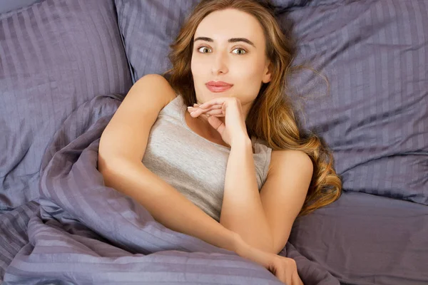 Güzel beyaz kadın manzarası. Gözleri açık, sabah uyuduktan sonra yatakta yatan güzel bir kadın. Yeni bir güne başlayalım - kavram.