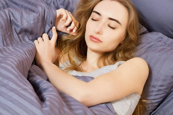 Çekici genç bir kadın yatağında uyuyor.