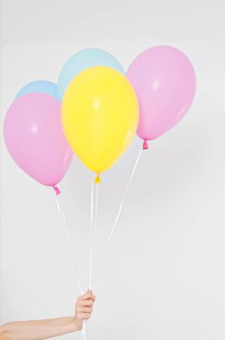 El ele tutuşan balonlar. Tatil konsepti. Renkli parti balonları arka planı. Beyazda izole edilmiş. Boşluğu kopyala