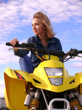 güzel sarışın mavi gökyüzü arka plan üzerinde spor quadrocycle üzerinde.
