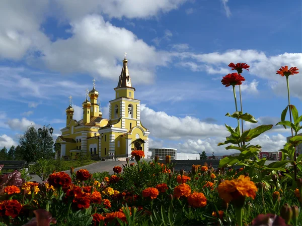 Nadym. det ortodoxa templet med flowerses på bakgrunden blå himmel. — Stockfoto