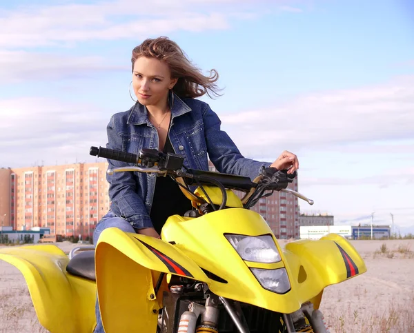 Beautiful blonde on sport quadrocycle on background of the city Nadym. — Stock Photo, Image