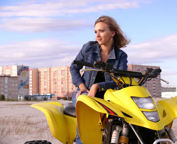 Mooie blonde op sport quadrocycle op de achtergrond van de stad nadym. — Stockfoto