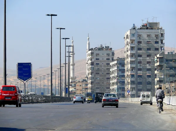 Ein unbekannter Mann auf einem Fahrrad. Verkehrsschilder schließen sich. Blick auf die Stadt, die Straße mit Autos in Syrien, Damaskus - 5. November 2008. — Stockfoto