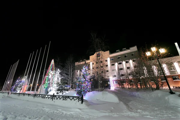 Ano Novo - umas férias em Nadym, Rússia - 28 de fevereiro de 2013. Decorações de rua festivas. Edifício lindamente iluminado e árvores. Extremo norte, Nadym . — Fotografia de Stock
