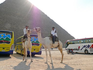 Mısır piramit portre. iki adam bilinmeyen deve yakın sürme şeklinde Mısır polis. Park halindeki turist otobüsleri ve piramit yakınındaki bir motosiklet.