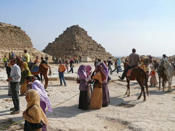 Два єгипетські піраміди крупним планом. стороннім особам, чоловіки і жінки зустрічають біля пірамід. Незнайомі люди на коні. — стокове фото