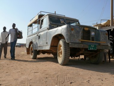 İki yabancı - Nubyeliler geçmiş wadi cipte gidiş - yarim, sudan - 19 Kasım 2008. eski jeep. mimari yapı.