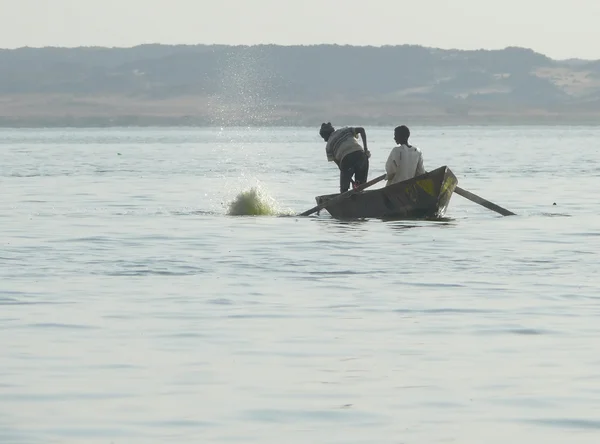 Незнайомими чоловіками, рибалок у човен плаває на річці Ніл, в Ваді - Халф, Судані - 19 листопада 2008 року. Ніл річки гори на задньому плані. — стокове фото