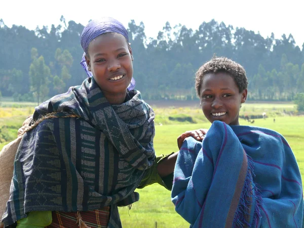 FINOTE SILAM, ETIOPÍA - 24 de noviembre de 2008: Dos extraños sonriendo de cerca a una niña etíope en Finote Silam, Etiopía - 24 de noviembre de 2008. Paisaje natural en el fondo . — Foto de Stock