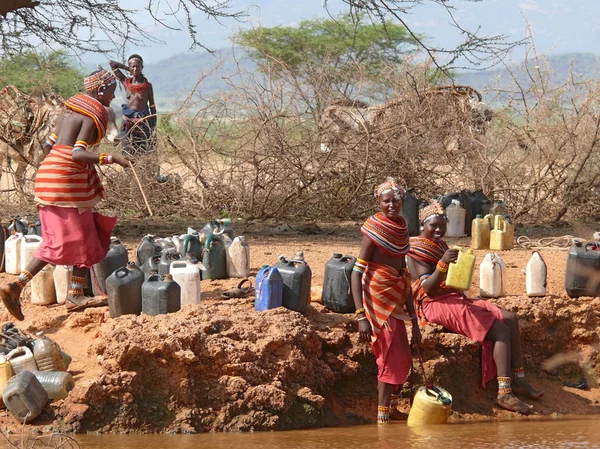 MARSABIT, ETIOPÍA - 28 DE NOVIEMBRE DE 2008: Una mujer desconocida de la tribu Tsonga recoge agua en botellas del río en Marsabit, Etiopía - 28 de noviembre de 2008. El río y el río. Árboles alrededor . —  Fotos de Stock