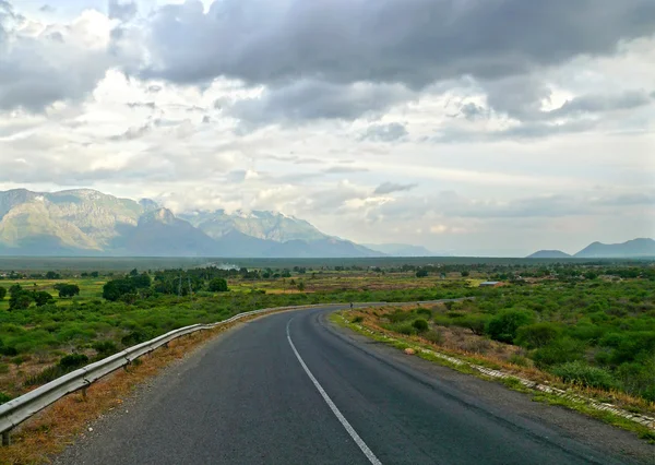 The cloudy sky. The road. Mountains in the distance. Tanzania, A — Stock Photo, Image