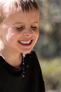 Soaking wet young boy laughing hysterically clipart
