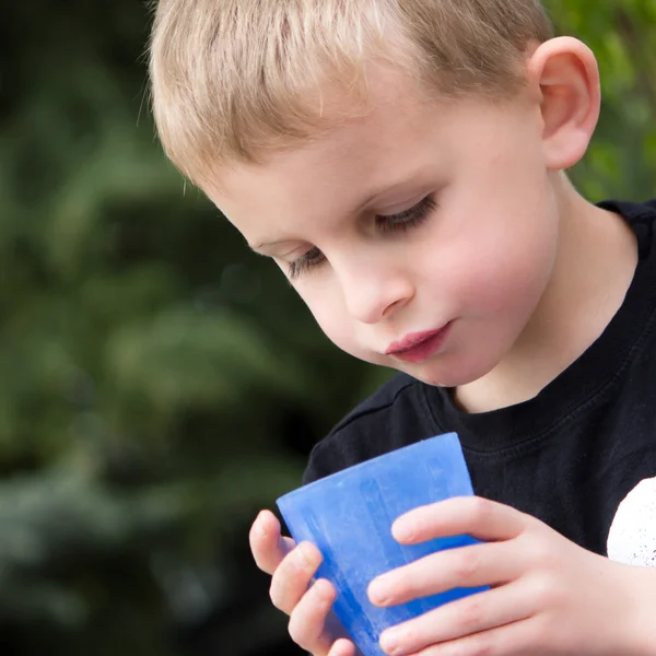 Jonge jongen drinken uit blauwe plastic beker — Stockfoto