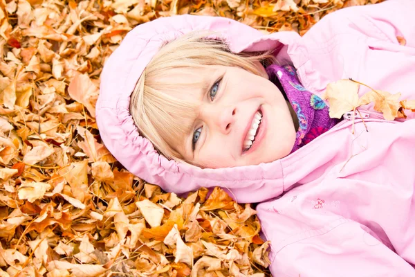 Kleines Mädchen liegt in Herbstblättern — Stockfoto