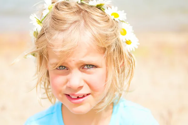 Vrij blond meisje met een kroon van madeliefjes — Stockfoto