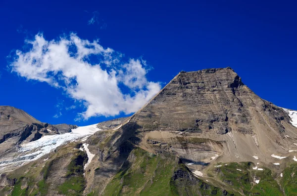 Mountain with white clouds on blue sky seen from alpine road — Stock Photo, Image