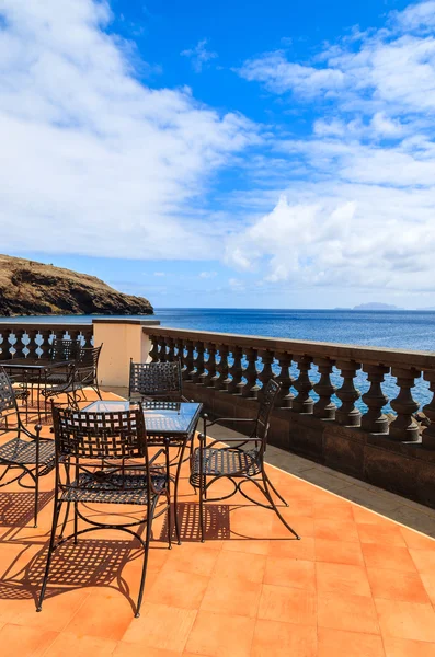 Uitzicht op zee en de metalen stoelen met glazen tafel op het terras van restaurant op zonnige zomerdag, eiland madeira, portugal — Stockfoto