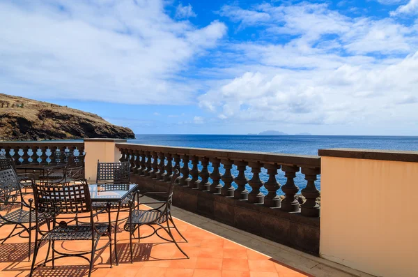 Uitzicht op zee en de metalen stoelen met glazen tafel op het terras van restaurant op zonnige zomerdag, eiland madeira, portugal — Stockfoto