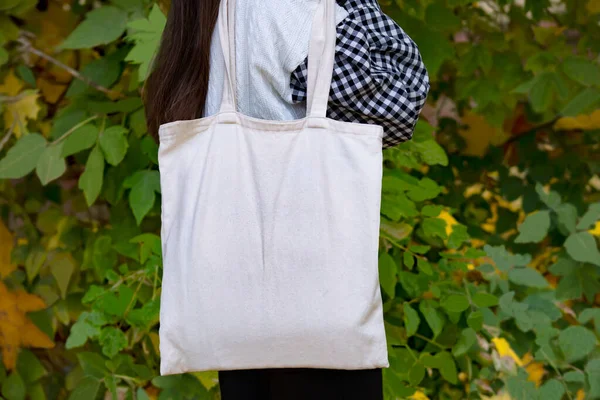 Empty reusable canvas tote bag mockup. Natural canvas eco-friendly shopper bag on girl\'s shoulder. Mockup for presentation of design or brand