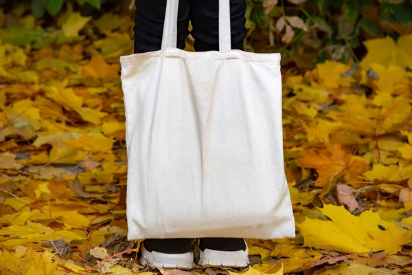 Empty reusable canvas tote bag mockup. Natural canvas eco-friendly shopper bag in girl\'s hand. Mockup for presentation of design or brand