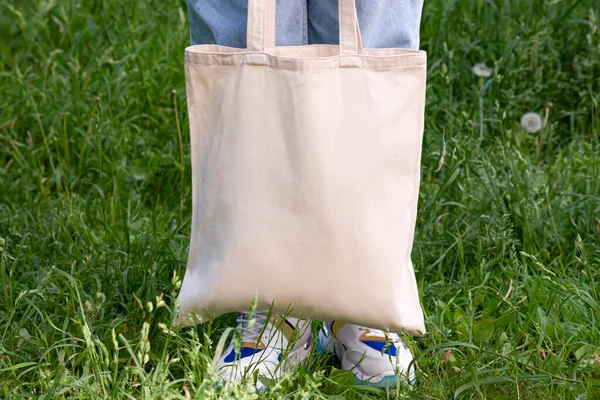 Empty reusable canvas tote bag mockup. Natural canvas eco-friendly shopper bag in girl\'s hand. Mockup for presentation of design or brand