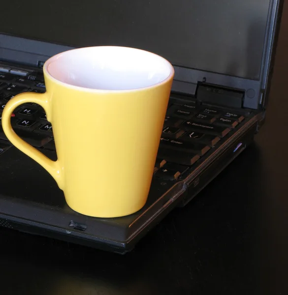 Yellow cup on the black notebook vacation for the eyes. — Stock Photo, Image