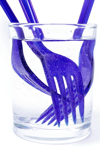 Garfos descartáveis em um copo de água — Fotografia de Stock