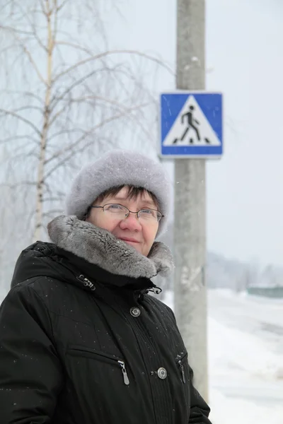 Kobieta pod znak przejście dla pieszych, zima. — Zdjęcie stockowe