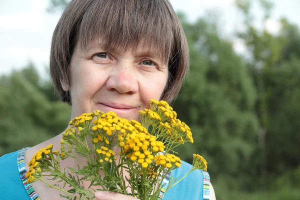 Middle-aged woman with medicinal flowers of tansy — Stock Photo, Image