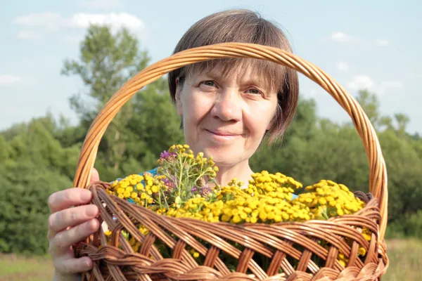 Medelålders kvinna med medicinalblommor av tansy — Stockfoto